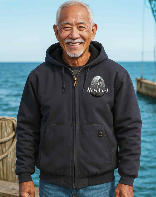 Man wearing a black hoodie with a logo by the ocean