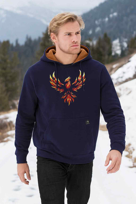 Man wearing a navy hoodie with a phoenix design in a snowy mountain landscape